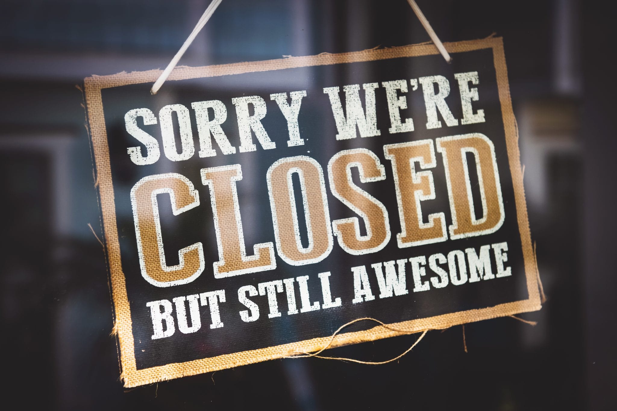 sorry we're closed but still awesome sign hanging in a window