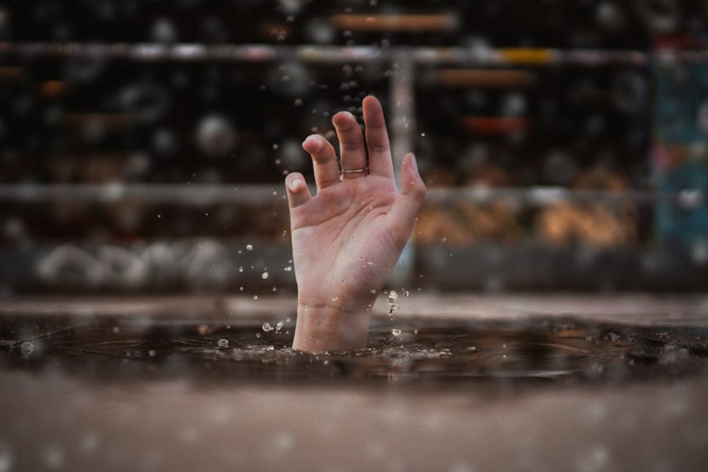 person drowning extending a hand above the water for help
