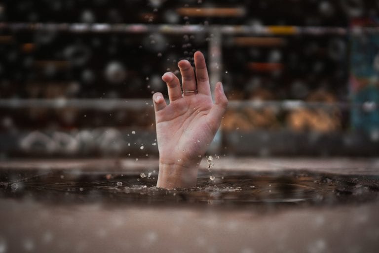 person drowning extending a hand above the water for help