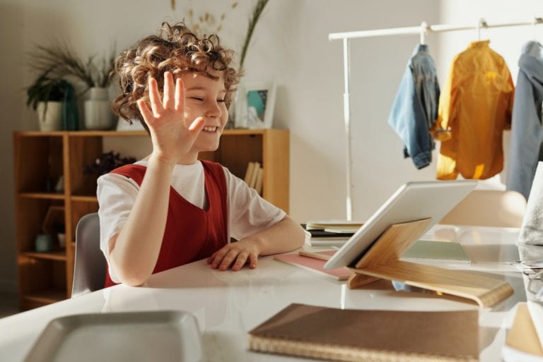 child smiling while using a tablet computer