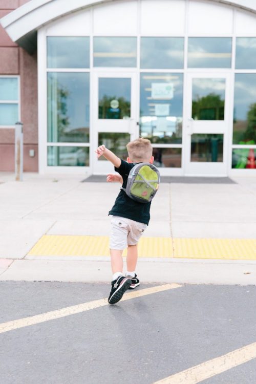 young boy walking excitedly into school